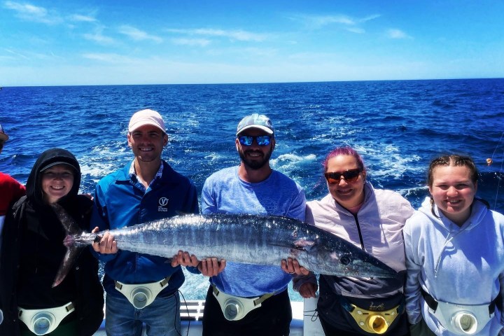 a group of people standing next to a person holding a fish