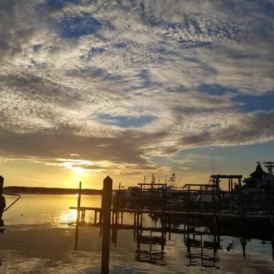 a beach with a pier in front of a sunset