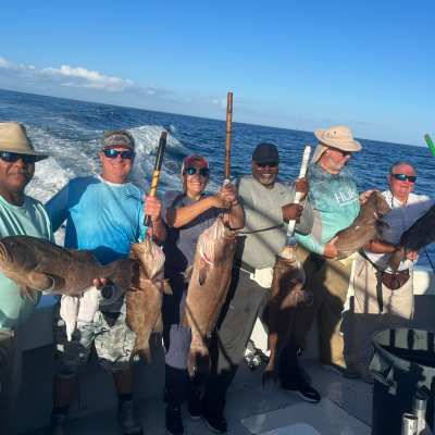 a group of people standing next to a man holding a fish